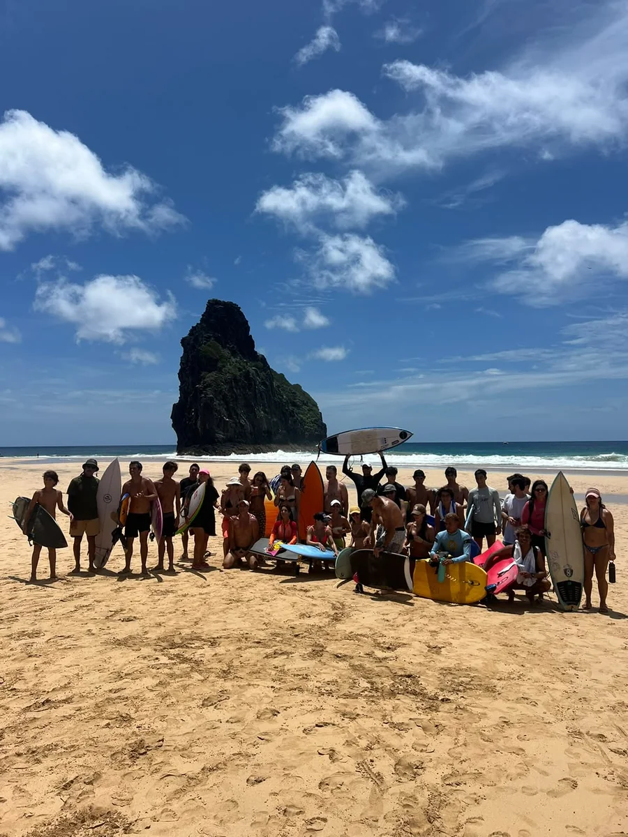 Grupo de uma viagem anterior com pranchas na praia em Noronha
